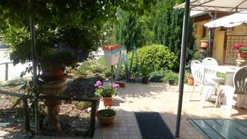A patio area with a table and chairs, surrounded by potted plants and a pergola.