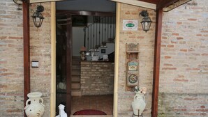 A rustic entrance with a wooden door, a brick wall, and two ceramic vases on either side. - Al Casolare (Corinaldo)