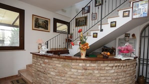 A reception area with a stone counter, a staircase, and various framed pictures on the walls. - Al Casolare (Corinaldo)