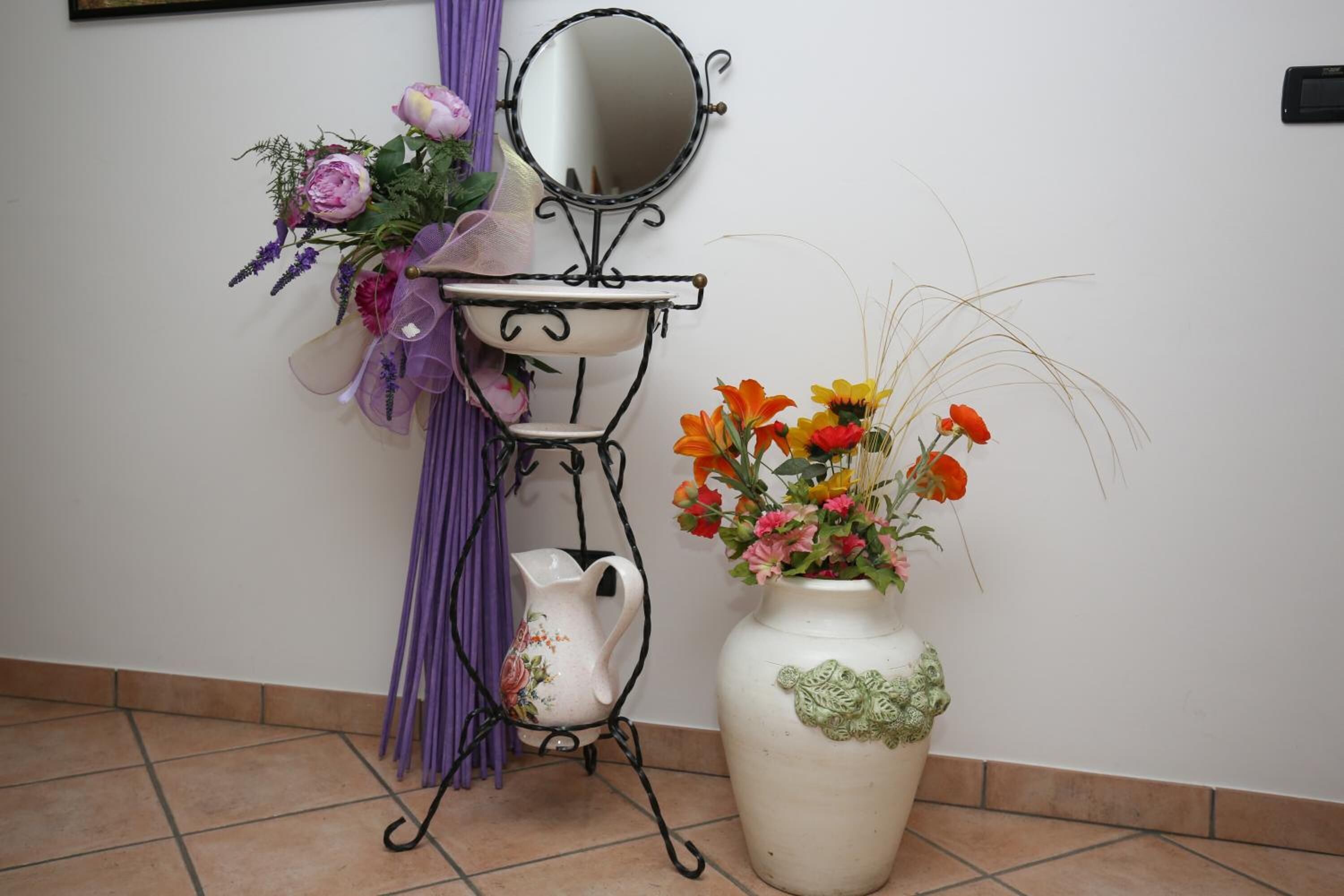 Et badeværelsesbord med et spejl, en kande og en vase med blomster.