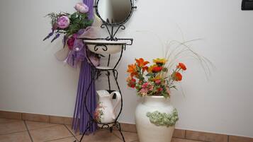 Et badeværelsesbord med et spejl, en kande og en vase med blomster.