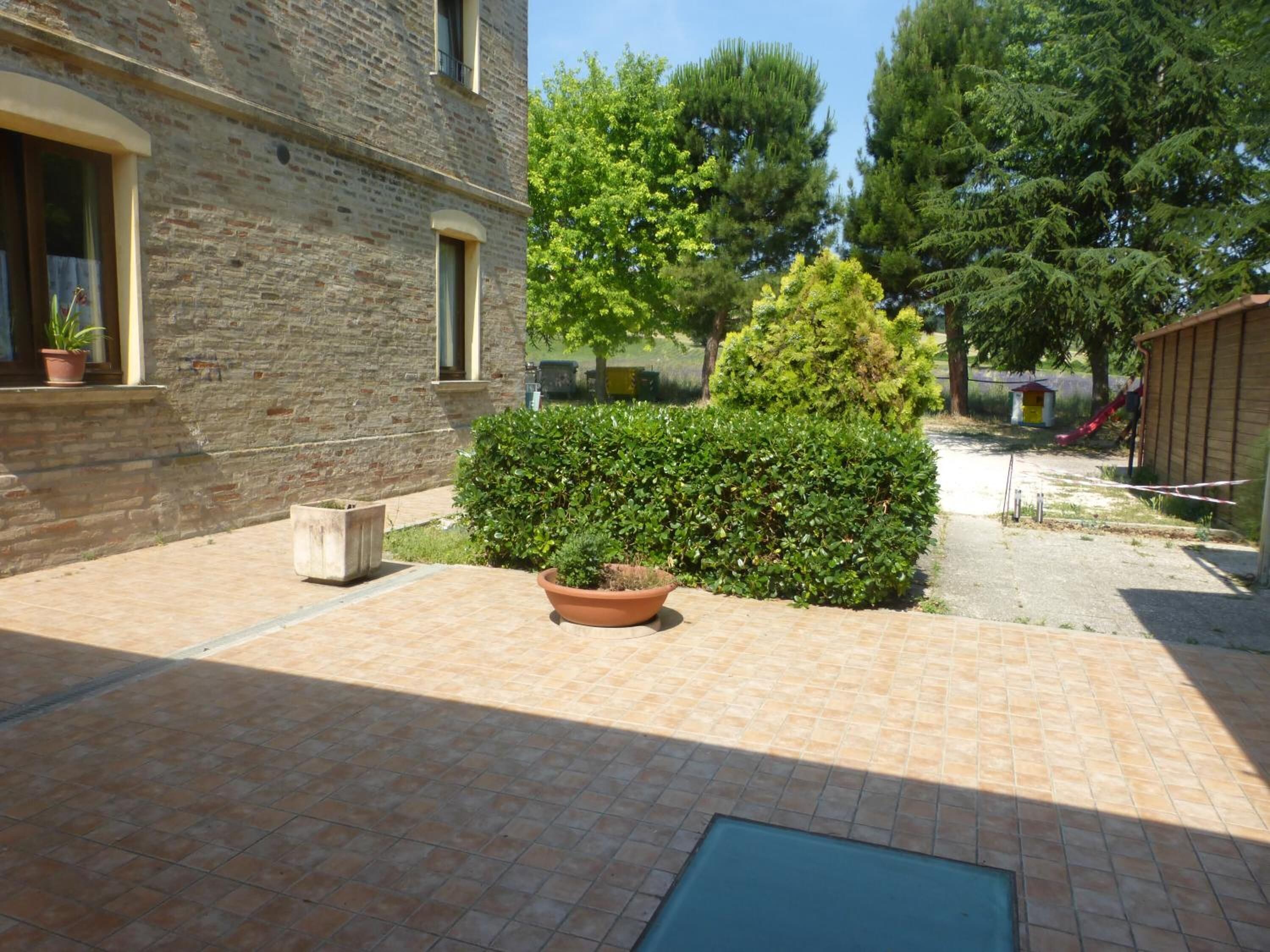 A courtyard with a brick building, a large bush, and a potted plant.