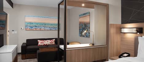 Una habitación de hotel moderna con una cama, un escritorio, un sofá y un espejo grande.