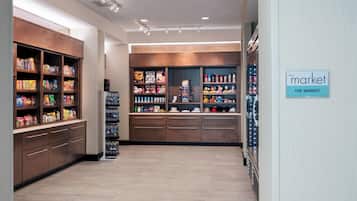 A well-lit store with shelves stocked with snacks and beverages, a refrigerated section, and a sign indicating 'The Market'.