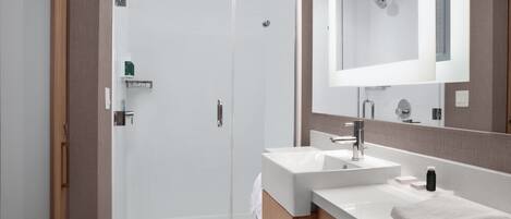 A modern bathroom with a glass-enclosed shower, a white sink, and a mirror above it.