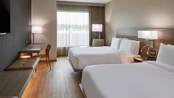 Habitación de hotel con dos camas, un escritorio, una silla y un televisor.