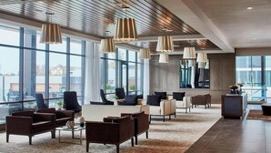 A spacious lobby with modern furniture, large windows, and contemporary lighting fixtures. - AC Hotel by Marriott Cleveland Beachwood (Orange)