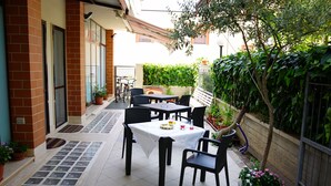 An outdoor patio with a table and chairs, surrounded by potted plants and a brick wall. - B&B President's Home (Matera)