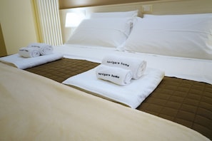 A hotel room with a bed, two pillows, and two rolled towels with "navigare home" text. - B&B President's Home (Matera)