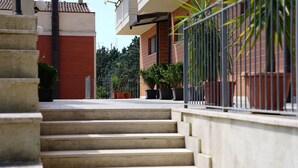 A residential building with a red brick facade, a metal fence, and a staircase leading to the entrance. - B&B President's Home (Matera)