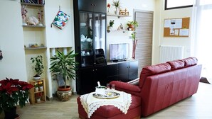 A living room with a red sofa, a television, and a cabinet with glass doors. - B&B President's Home (Matera)