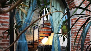 A room with a brick wall, a window with blue curtains, a red rug, and a hanging lamp. - B&B Convento S. Antonio (Como)