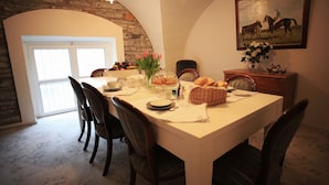 A dining area with a stone arch, a chandelier, and a painting of horses. - B&B Convento S. Antonio (Como)