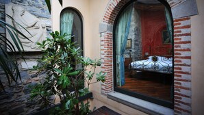 A room with a bed, a stone wall, and a window with a curtain. - B&B Convento S. Antonio (Como)