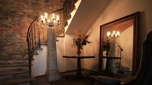 A staircase with a stone pillar, a round table with a vase of flowers, and a mirror on the wall. - B&B Convento S. Antonio (Como)