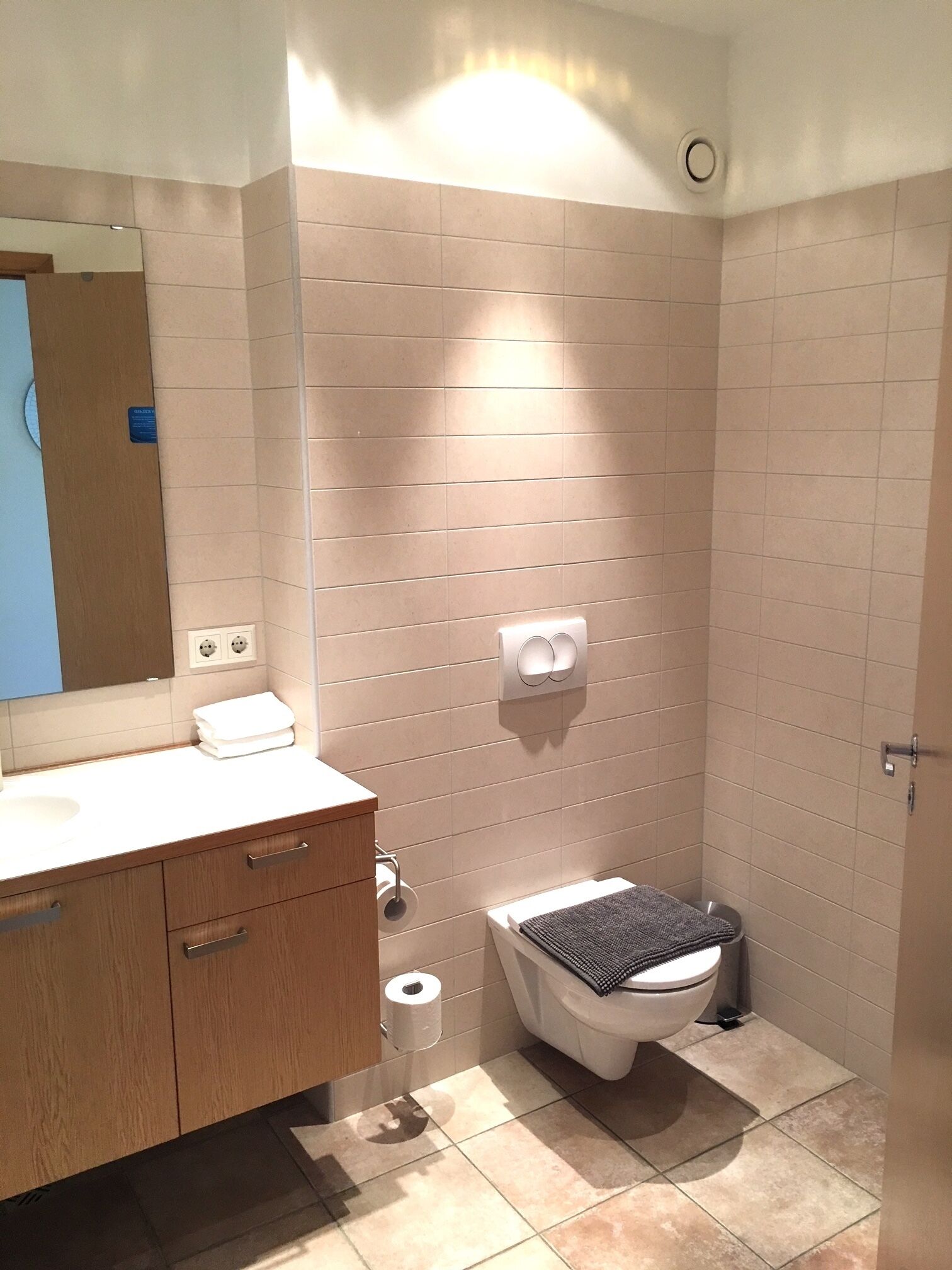 Un baño moderno con tocador de madera, inodoro y zona de ducha.
