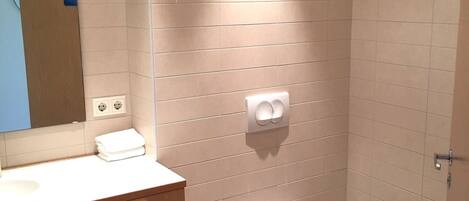 Un baño moderno con tocador de madera, inodoro y zona de ducha.