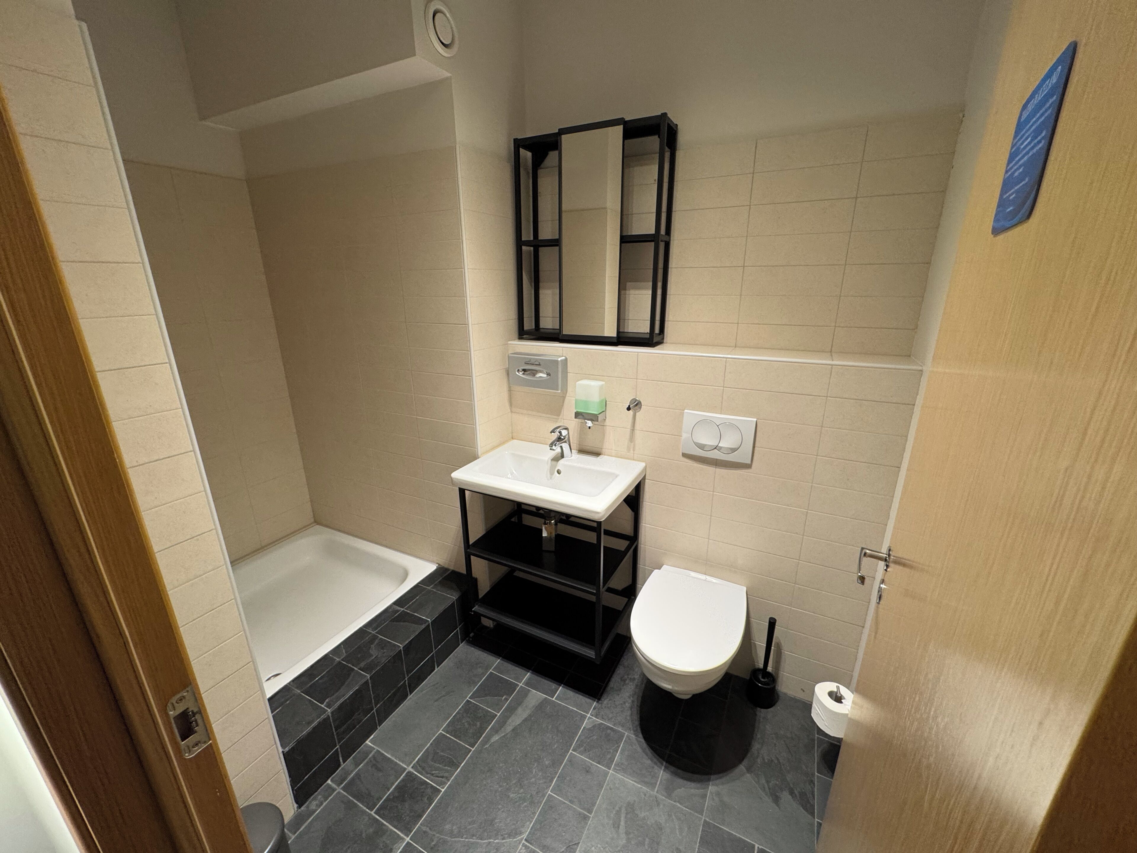 A bathroom with a bathtub, a sink, a toilet, and a mirror.