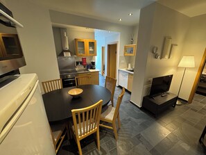 A modern kitchen with a dining table, chairs, a refrigerator, a stove, and a television. - Downtown Reykjavík Apartments (Reykjavik)