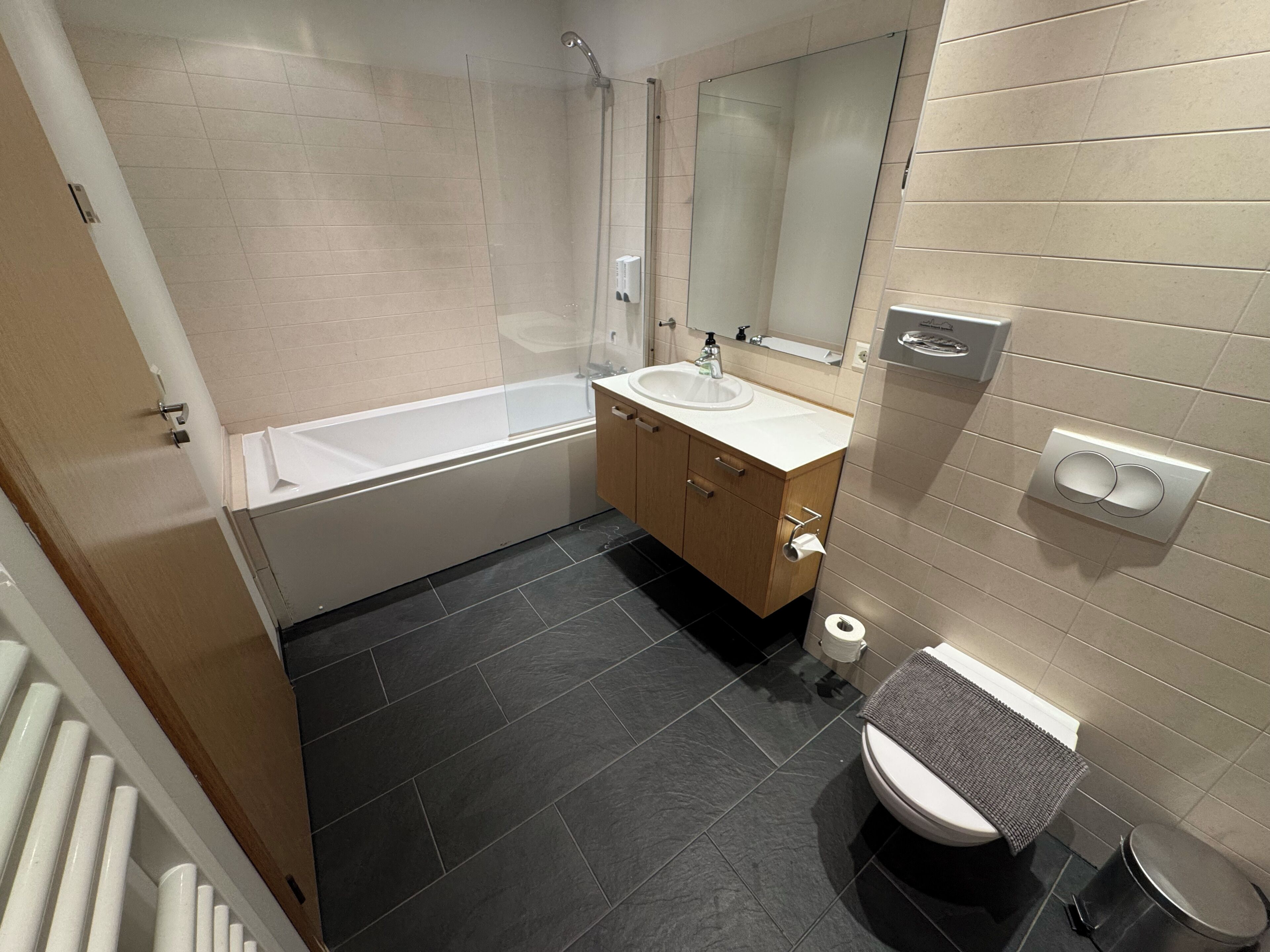 Un baño moderno con bañera, lavabo, espejo, inodoro y toallero.