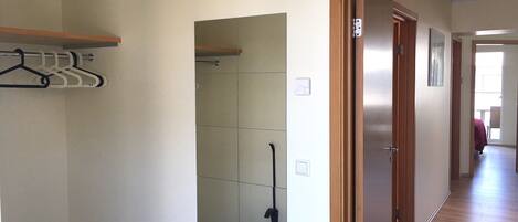 A hallway with a wooden door, a coat rack, and a mirror on the wall.