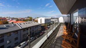 A balcony with a view of a cityscape, including buildings and a clear sky.