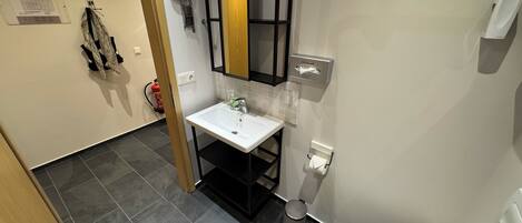 Ein Badezimmer mit Waschbecken, Spiegel, Toilette und Handtuchspender.