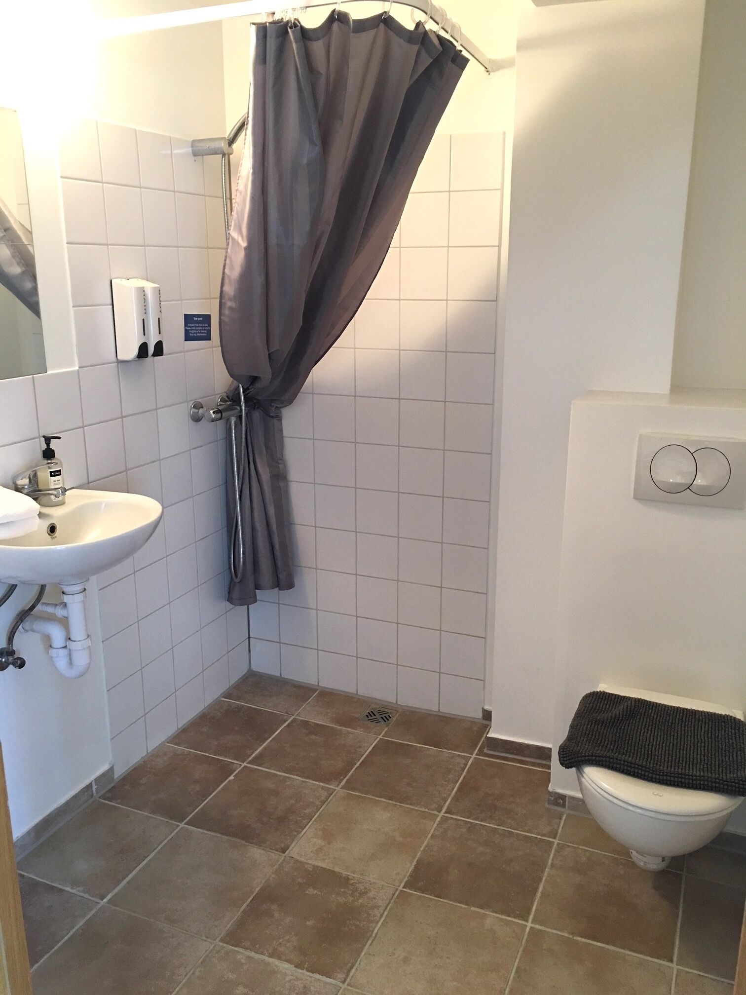 A bathroom with a shower curtain, a sink, and a toilet.