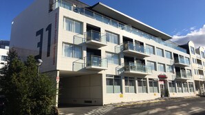 A modern multi-story building with balconies, large windows, and a clear sky.