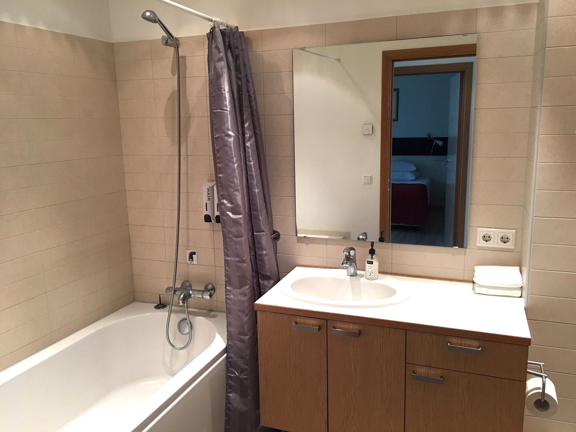 Une salle de bain avec une baignoire, un lavabo, un miroir et un rideau de douche.