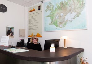 A reception desk with a map of Iceland, a cityscape poster, and a sign with text.