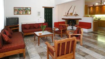 A living room with a television, sofas, chairs, a coffee table, and a fireplace.