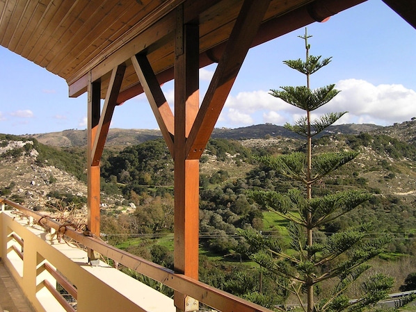 A wooden balcony with a view of a mountainous landscape.
