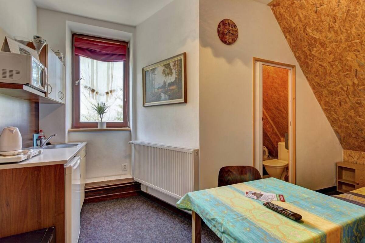 Una habitación pequeña y acogedora con kitchenette, zona de comedor y ventana con vistas a árboles.