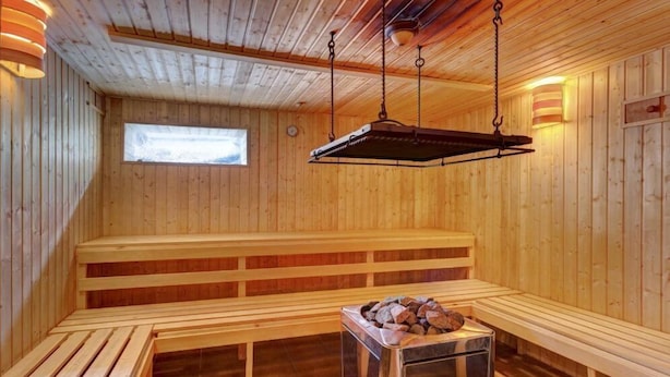 A sauna with wooden benches and a central fire table.