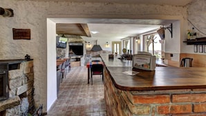 A rustic interior with a stone fireplace, a long dining area, and a bar with a stone counter.