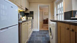 A kitchen with a washing machine, cabinets, and a tiled floor.