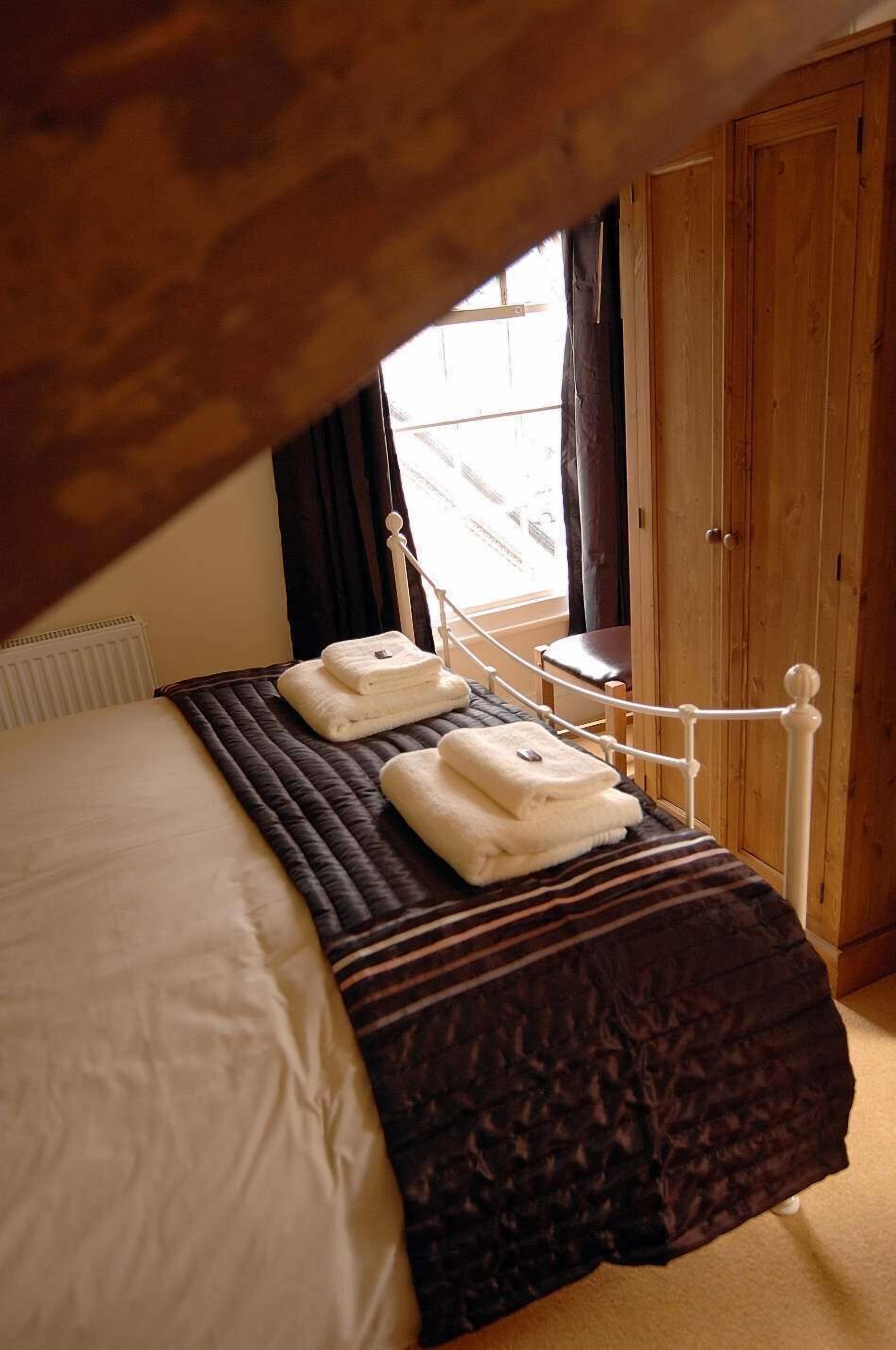 Un dormitorio con cama, un armario de madera y una ventana con cortinas.