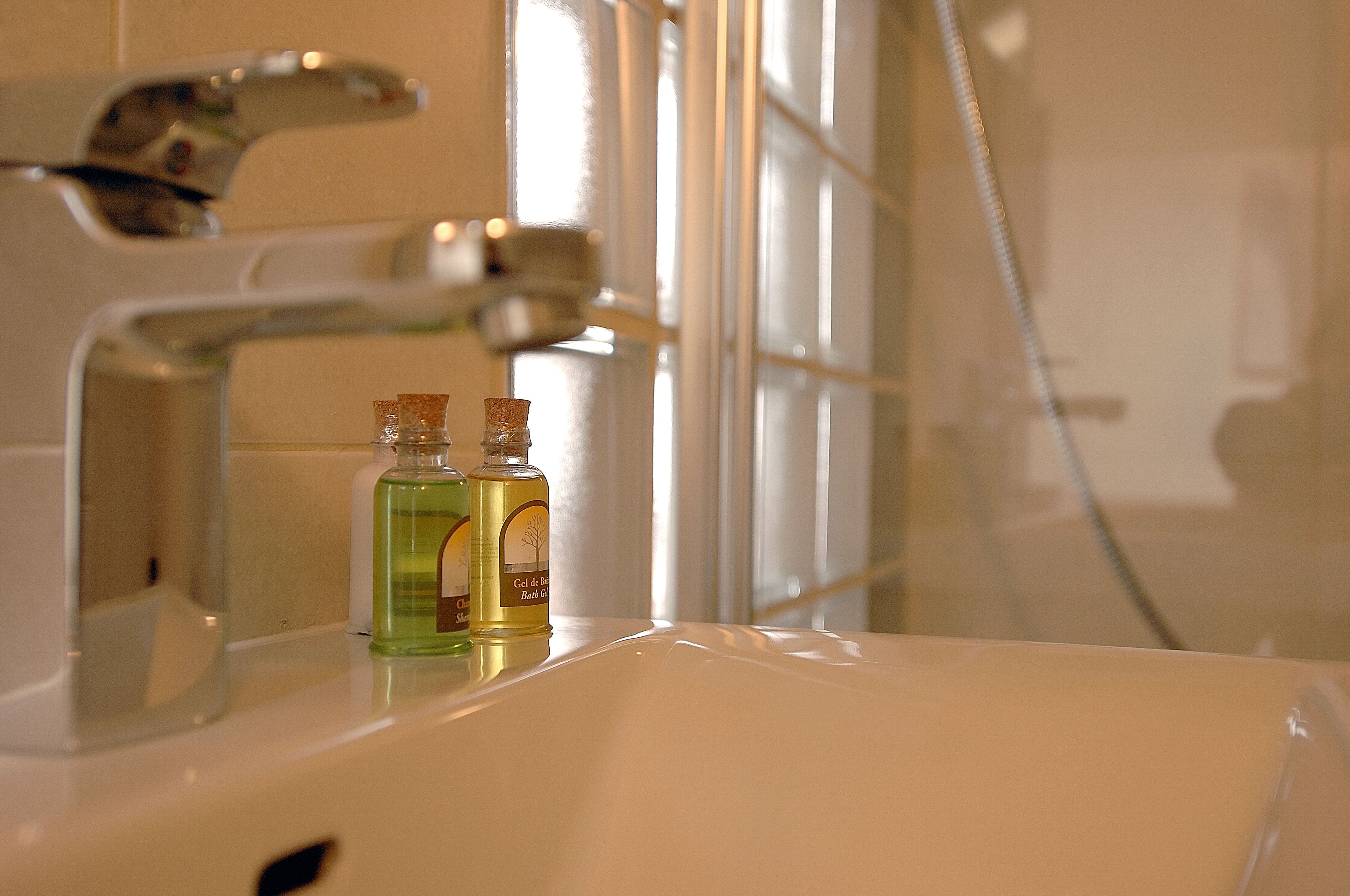 Un lavabo de salle de bain avec deux bouteilles de gel douche et un robinet.