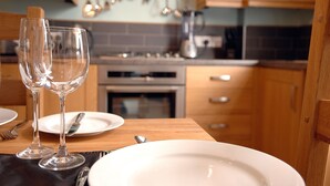 A dining table with two wine glasses, a plate, and cutlery.
