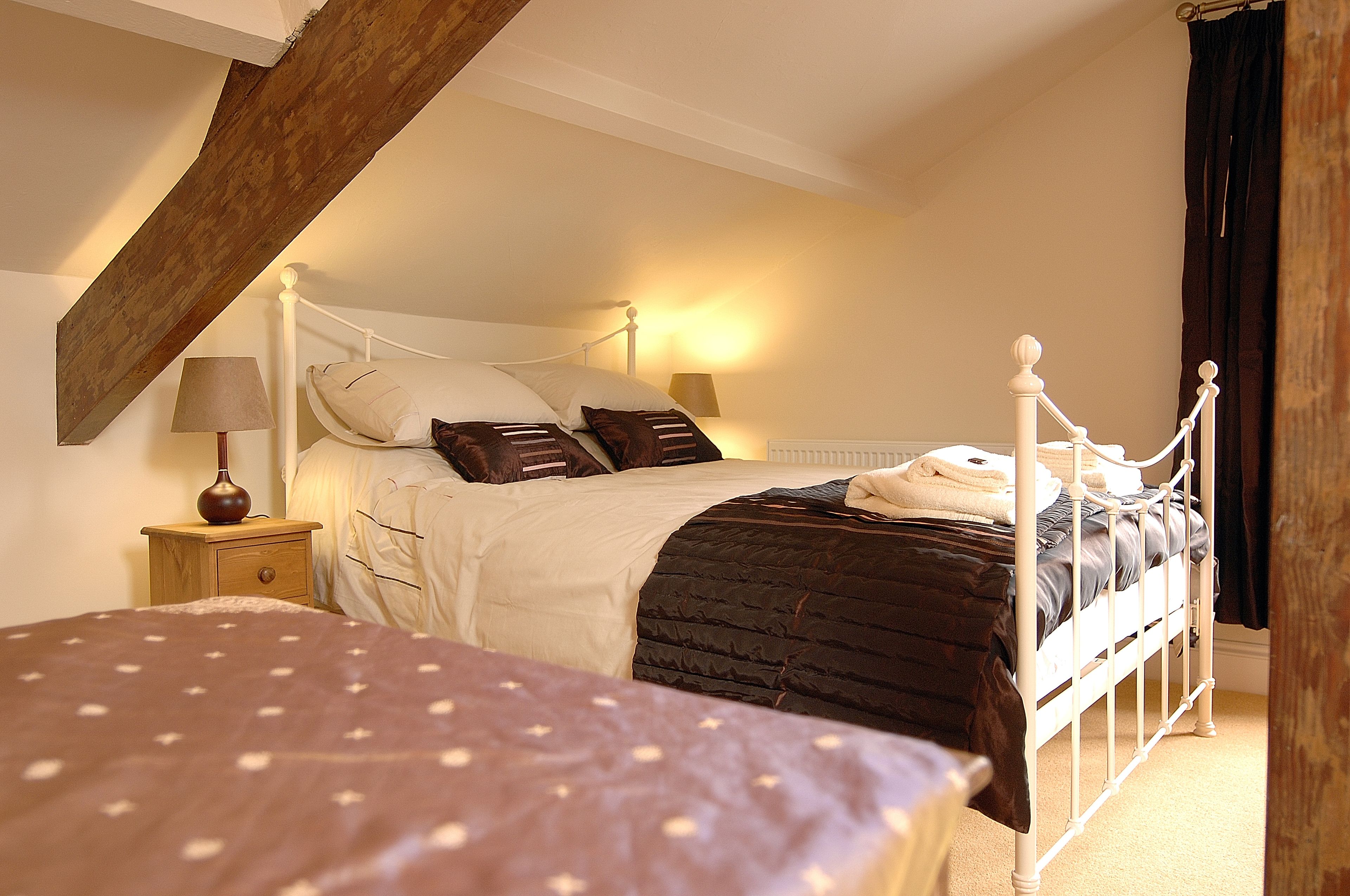 A bedroom with a bed, bedside tables, and a lamp.