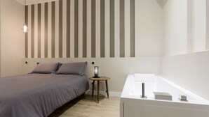 Un dormitorio moderno con cama, mesita de noche y tocador blanco.