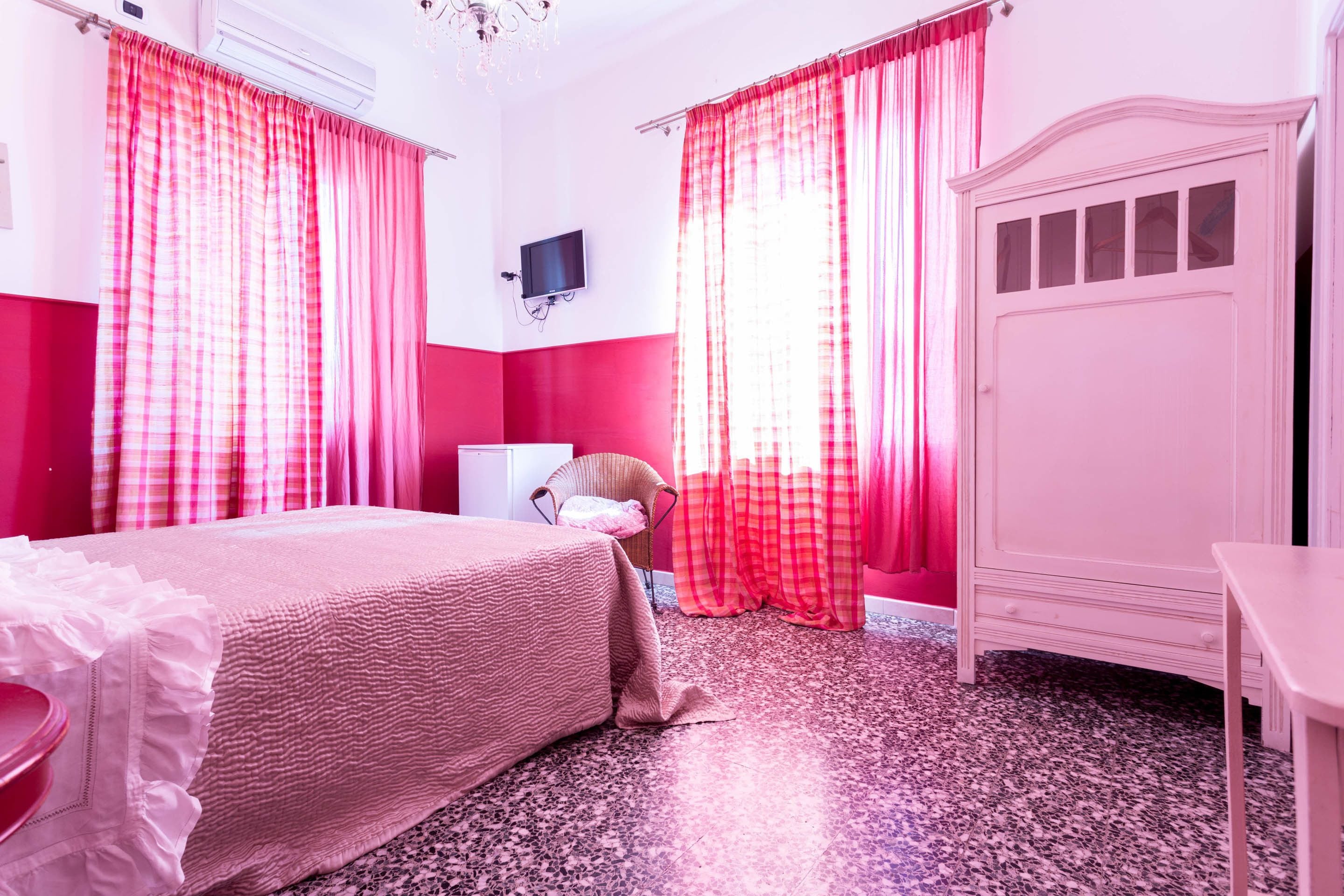 A bedroom with a bed, a chair, a desk, and a wardrobe.