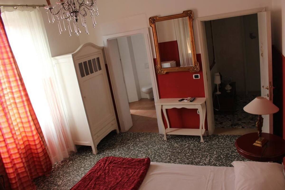 Un dormitorio con una cama, un tocador, un espejo y una mesita de noche con una lámpara.