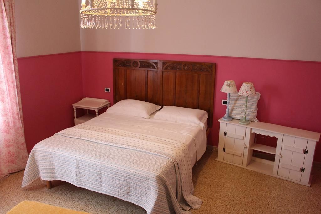 Una camera da letto con un letto, un comodino, una cassettiera e un lampadario.