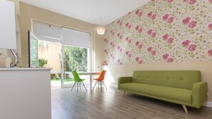 Una sala moderna con un sofá verde, una mesa de centro blanca y dos sillones.