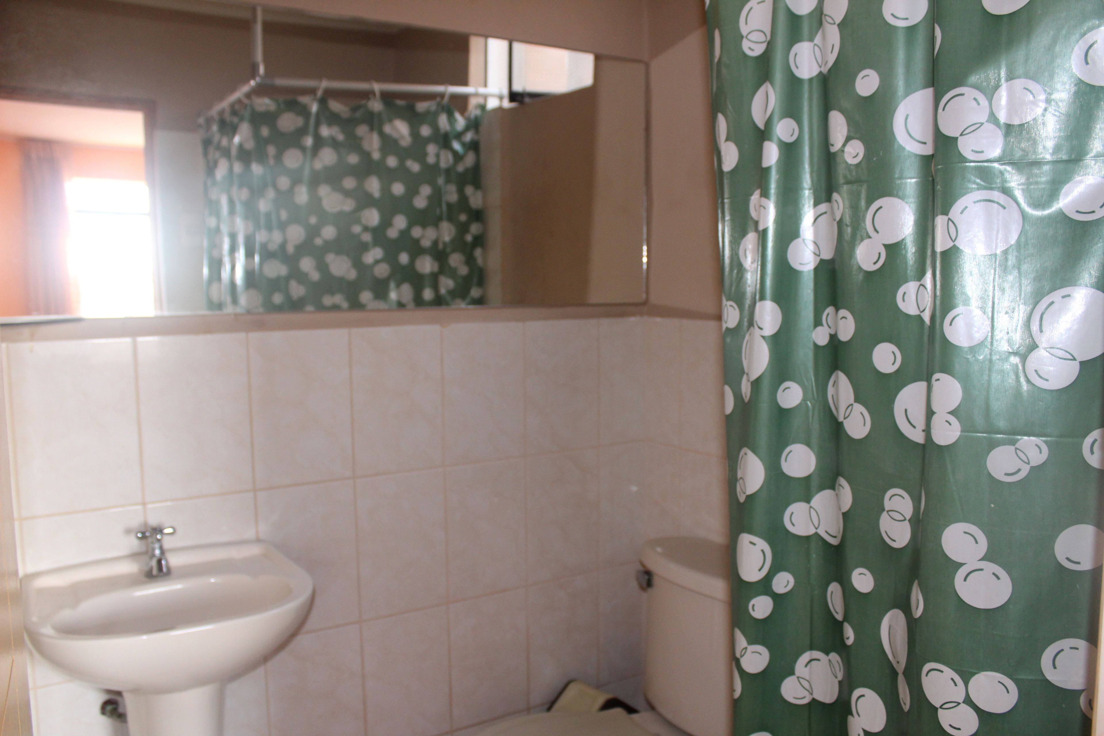 A bathroom with a sink, toilet, and a shower curtain with a polka dot pattern.