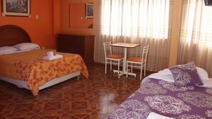 A hotel room with two beds, a small table with chairs, and a window with curtains. - Hostal Shalom (Pisco)