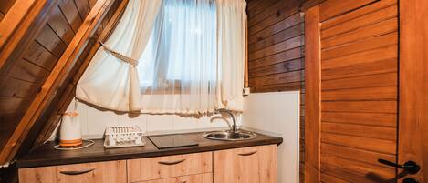 A kitchen with wooden cabinets, a sink, and a window with a curtain.