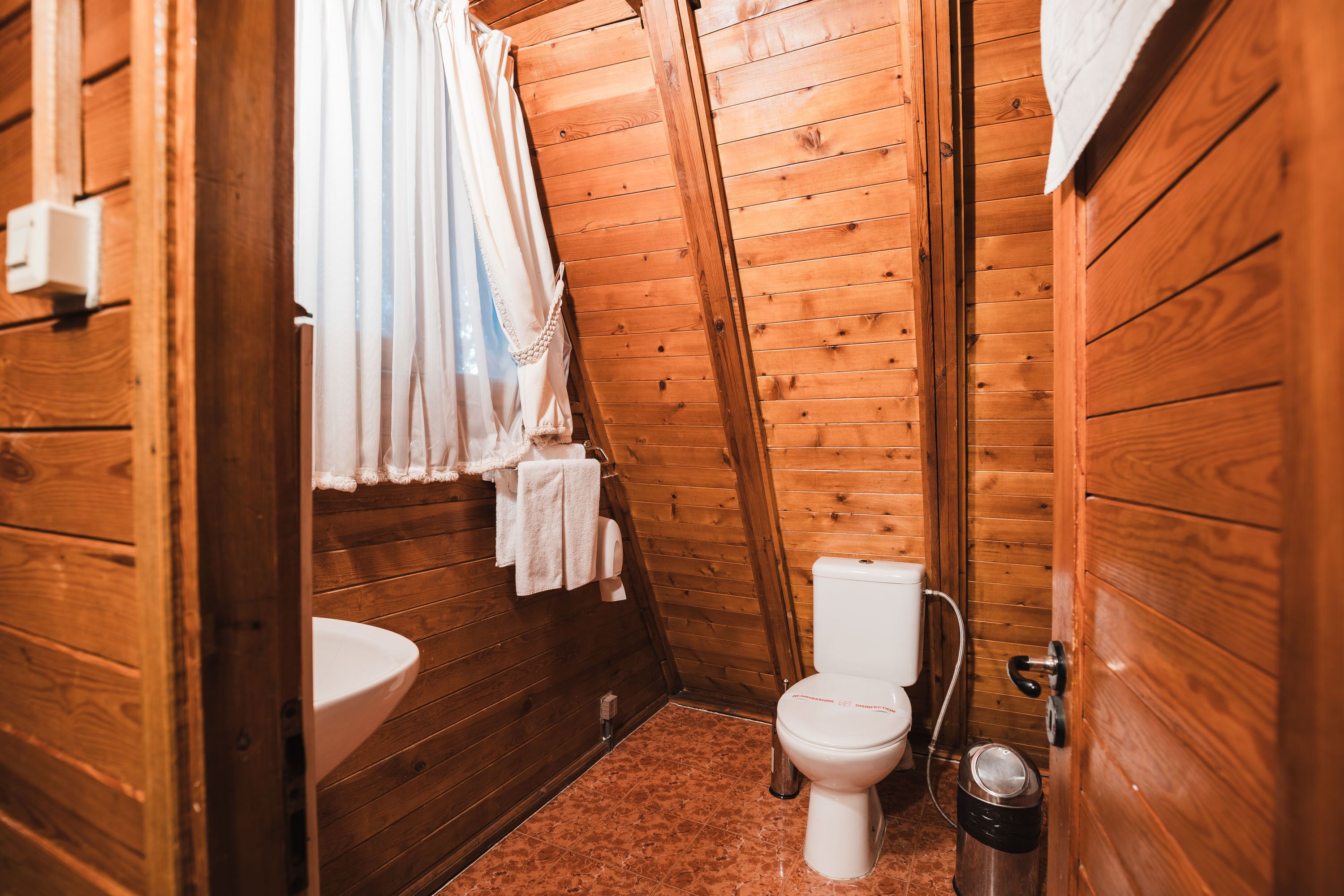 A wooden-paneled bathroom with a toilet, sink, and shower curtain.